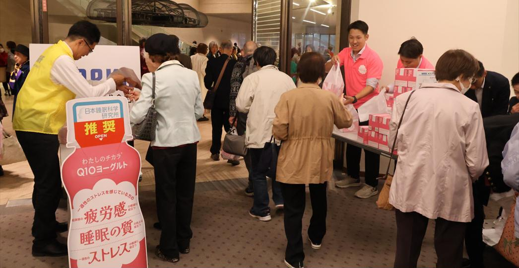 老人クラブのイベント会場で、スタッフから商品を受け取るシニアの参加者